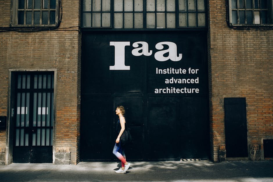 A woman walks past the Institute for Advanced Architecture building in daylight.